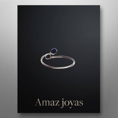 Anillo elegante de acero y oro con detalles de piedras preciosas en tonos azul y rojo.